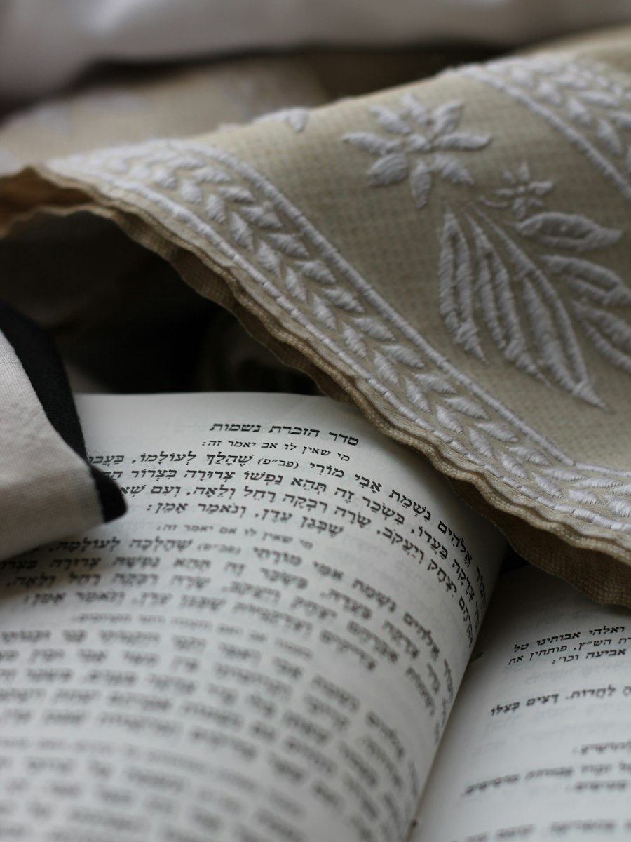 An embroidered tallit draped over an open Hebrew prayer book